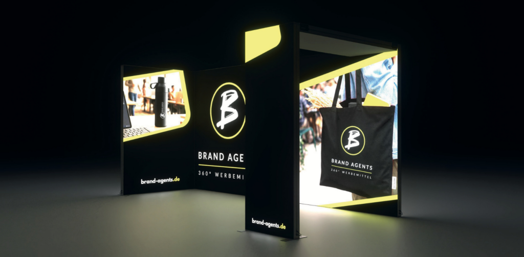 Brand Agents Messestand mit neon-gelben LED-Flächen, schwarzem Branding, Logo, 360° Werbemittel und brand-agents.de auf Rollups sowie Tasche im Set.